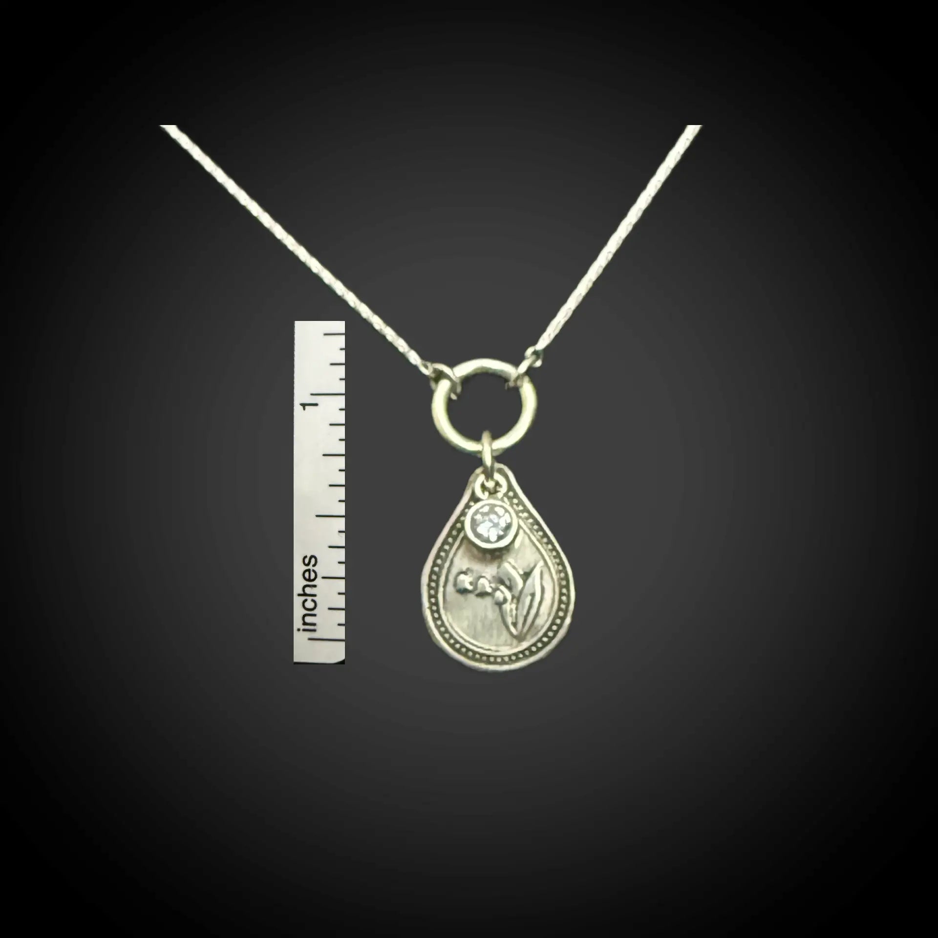 Size reference of May lily of the valley birth flower sterling silver necklace with alexandrite CZ stone next to inch ruler.