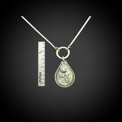 Size reference of May lily of the valley birth flower sterling silver necklace with alexandrite CZ stone next to inch ruler.