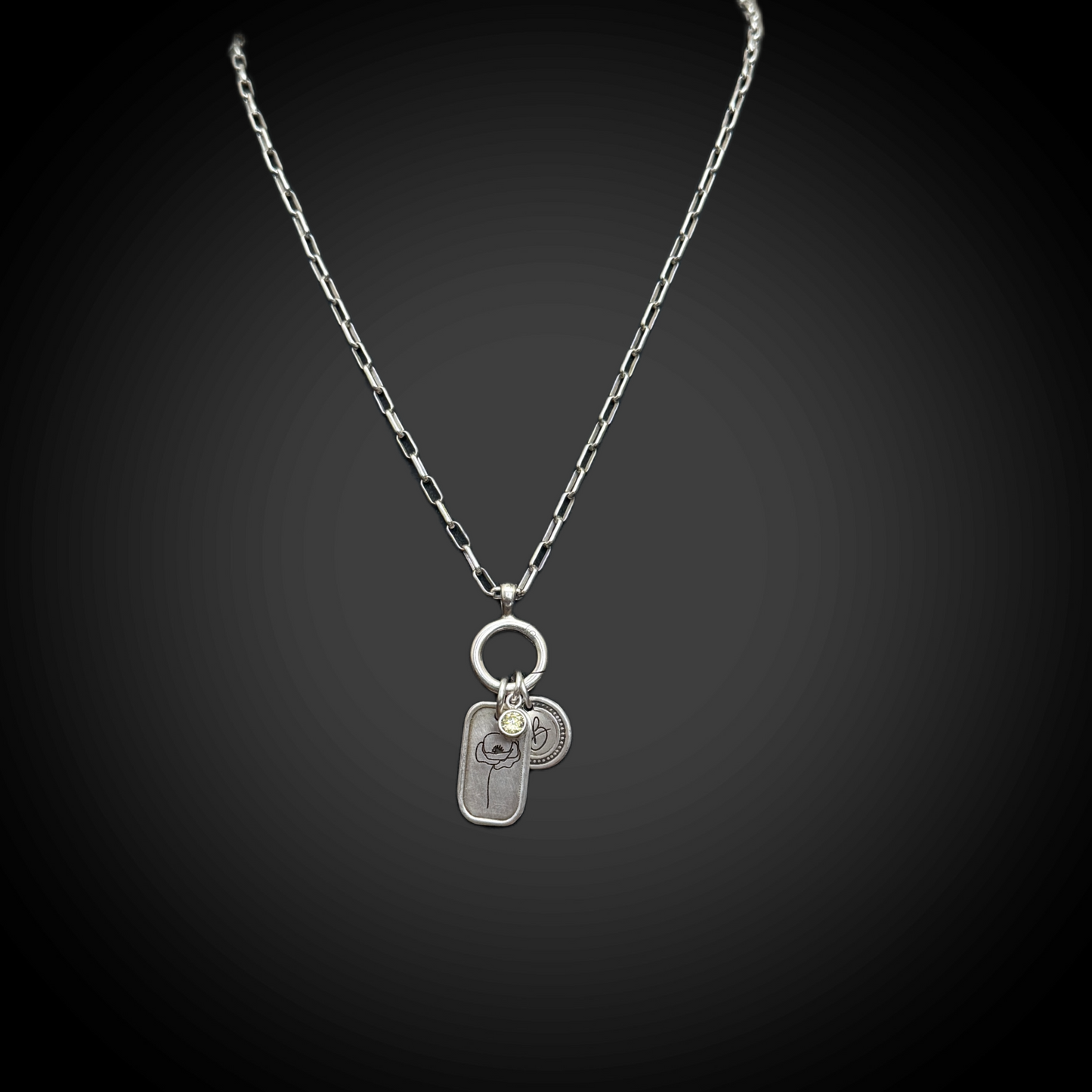 Silver necklace with two pendant tags on a black background