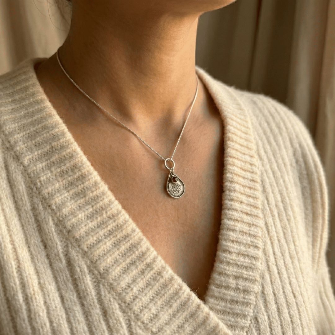 January carnation birth flower sterling silver necklace with garnet-red CZ birthstone shown on neckline for scale.