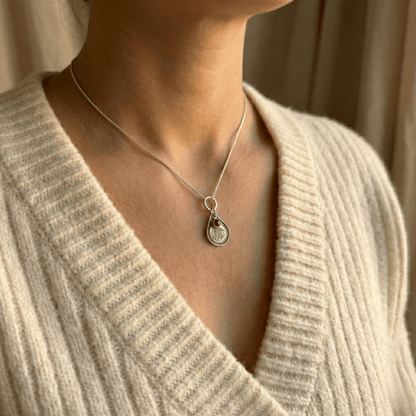 January carnation birth flower sterling silver necklace with garnet-red CZ birthstone shown on neckline for scale.