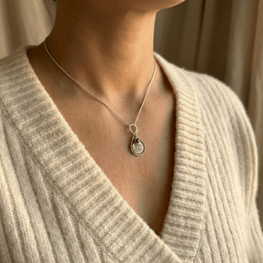 January carnation birth flower sterling silver necklace with garnet-red CZ birthstone shown on neckline for scale.