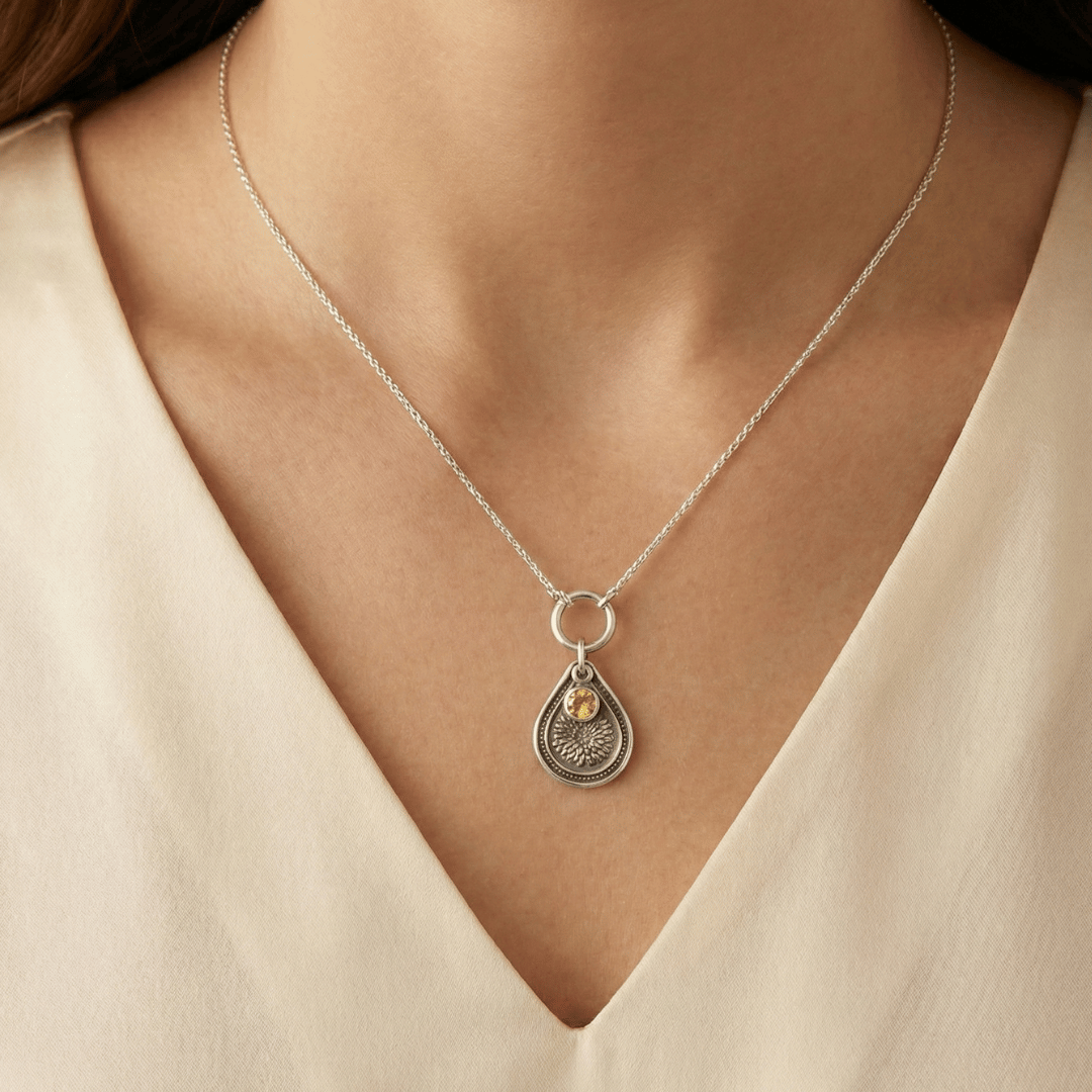 November chrysanthemum birth flower sterling silver necklace with golden citrine CZ stone shown on neckline for scale.