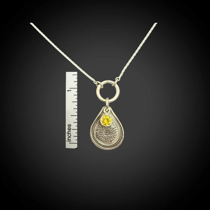 Size reference of November chrysanthemum birth flower sterling silver necklace with golden citrine CZ stone next to inch ruler.