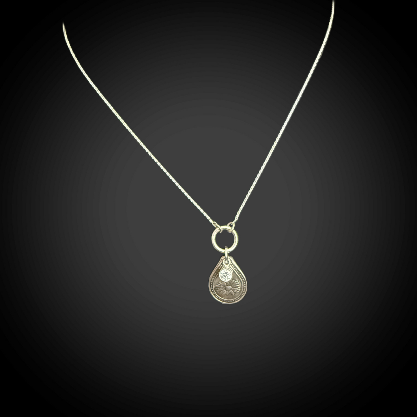 Sterling silver April birth flower necklace with daisy engraving and clear diamond-like CZ stone by Adorn Designs Jewelry.