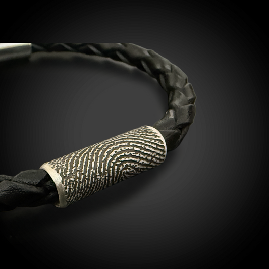 Black braided leather bracelet with a fingerprint bead and metal clasp on a dark background