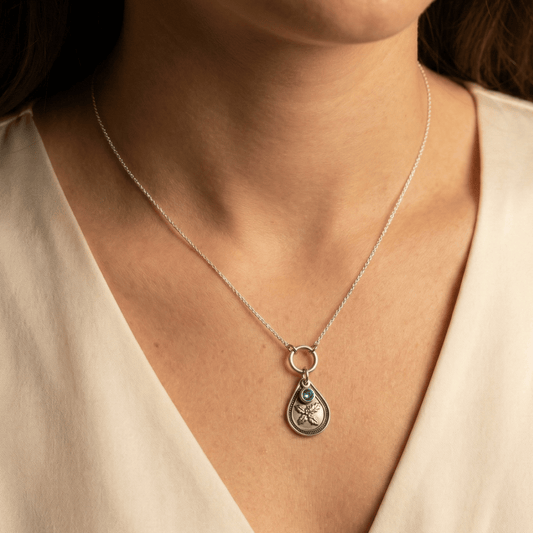 December holly birth flower sterling silver necklace with blue zircon CZ stone shown on neckline for scale.