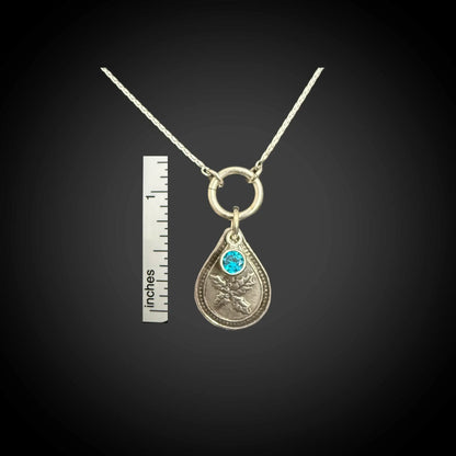 Size reference of December holly birth flower sterling silver necklace with blue zircon CZ stone next to inch ruler.