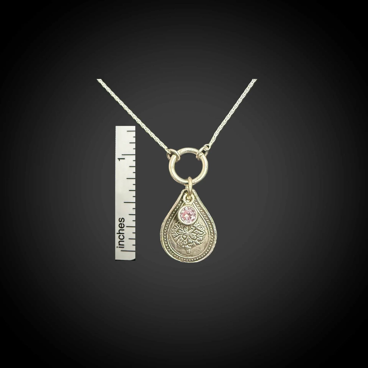 Size reference of October marigold birth flower sterling silver necklace with pink tourmaline CZ stone next to inch ruler.