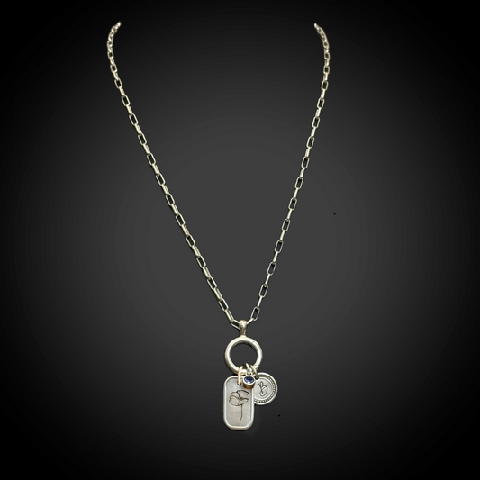 Silver necklace with three charms on a black background