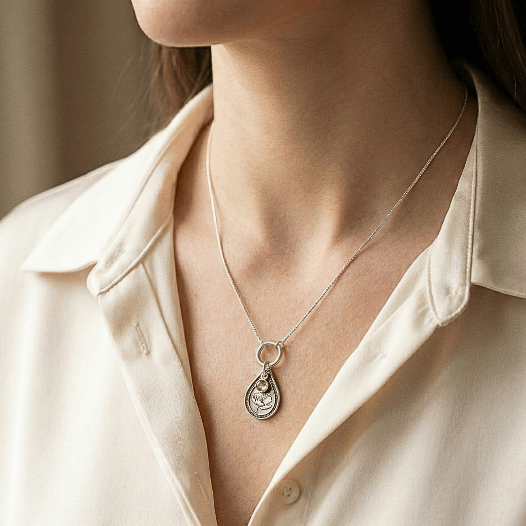 August poppy birth flower sterling silver necklace with peridot-green CZ stone shown on neckline for scale