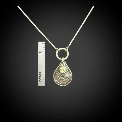 Size reference of August poppy birth flower sterling silver necklace with peridot-green CZ stone next to inch ruler.
