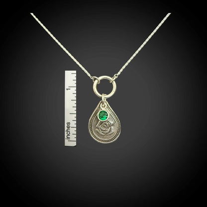 Size reference of June rose birth flower sterling silver necklace with emerald-green CZ stone next to inch ruler.