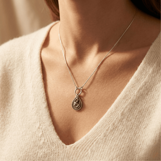 February violet birth flower sterling silver necklace with amethyst-purple CZ stone shown on neckline for scale.