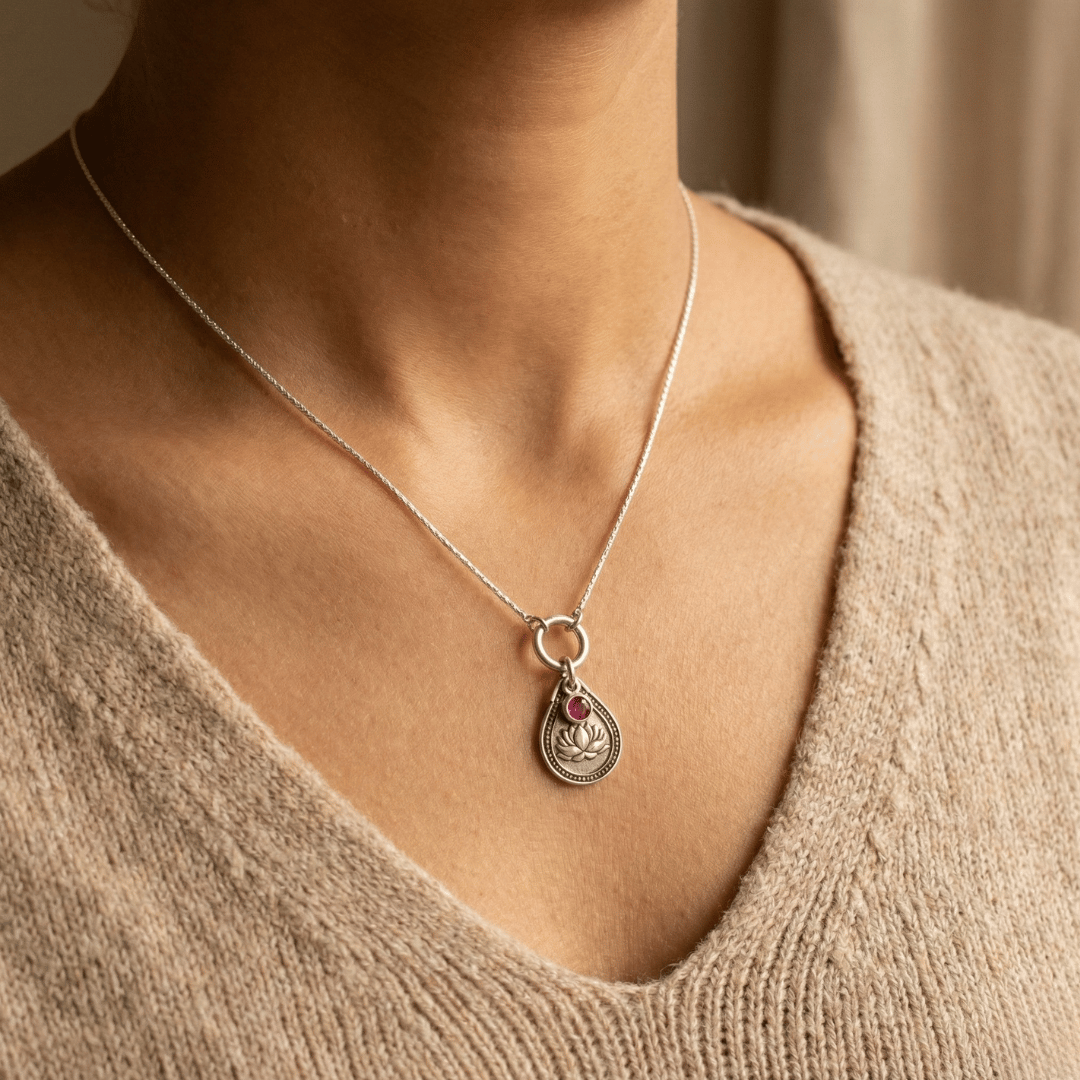 July water lily birth flower sterling silver necklace with ruby-red CZ stone shown on neckline for scale.